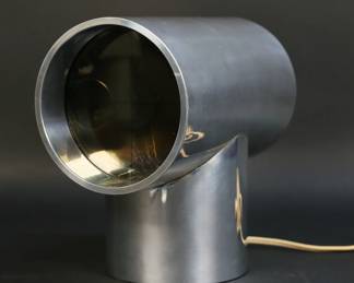 414	Kirsch / Hamilton Aurora Mid-Century Clock	Al Corchia and Rudolph De Harak for Kirsch / Hamilton. Mid-century modern chrome Aurora clock / lamp. Paper label to the underside. 8 1/4"H x 8"L x 5"-diameter. Clock running (timekeeping untested), lighting not working; losses to interior of clock face, minor scratches to chrome, chips to plastic on base.
