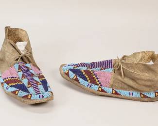368	Pair of Beaded Hide Moccasins	Pair of Native American hide moccasins, with pink, blue, yellow and red beaded decoration. Each 11"L. Minor losses to beaded decoration on the tops of each, wear to soles, wear to toes, seams splitting at heel of both.

