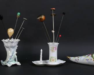 241	23 Vintage Hatpins With Holders	23 vintage hat pins with holders. Including NJ National Guard button, gold tone, wood, minerals, organizational, rhinestone, enamel. In four porcelain holders including hanging holder with hand painted floral decoration, one marked Bavaria, hatpin holder with ring tree, Royal Bayreuth. Hatpin with cameo 9 3/4"L, Royal Bayreuth holder 4 3/8"H.
