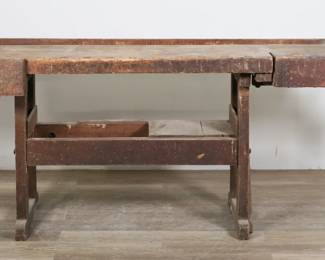 98	Hammacher Schlemmer and Co. Workshop Bench	"Hammacher Schlemmer and Company workshop bench. New York, early 1900s. Wooden workbench with lower shelf and two vises on either end. Vises each fitted with metal collar cast with ""Hammacher Schlemmer & Co. New York"". Heavy scratches, wear, glue and paint remnants, scuffs, and marks throughout entirety of table. Collar on one vise is separated in two pieces but secured by one screw. Losses to wood on lower tier. Two remaining panels on lower tier are loose. Paper and wood pieces stuck into channel on top. Top is not attached to base. 

84 3/4"" W x 31 1/2"" D x 32 5/8"" H. 150 lbs."
