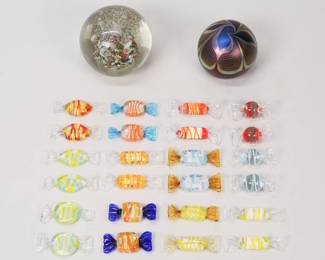 222	2 Art Glass Paperweights, Murano Glass Candy	Lot of decorative glass. 24 pieces Murano blown glass candy, largest 2 1/4"L; 2 art glass paperweights: iridescent pulled feather paperweight, signed on the underside Correia with Summa Gallery paper label, 2 5/8"H; with an unsigned art glass paperweight. Candy all with chips to "wrapper" ends, one piece with large chip; paperweights both with scratches to the undersides, unsigned paperweight with additional scratches and chips throughout.
