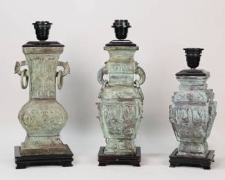 176	3 Chinese Bronze Archaic Style Lamps	3 archaic style Chinese bronze table lamps. Urn forms, green patina. All mounted on wooden bases. 12 7/8"H, 15 7/8"H and 16 1/8" (heights to top of sockets). All with chips and loses to wooden bases and fittings.
