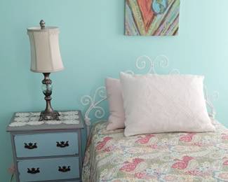 This white painted headboard is a heavyweight vintage iron, that was made to slide securely in place with the included bedframe.
Painted wood side chest, with a distressed multicolor finish.