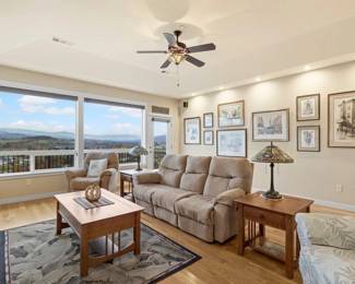 Mission style Coffee Table and Side Tables. Recliner Sofa. Two Recliner Chairs. Patterned Carpet. On the Left Leaded Glass Small Lawyer's Cabinet. Leaded Glass Tiffany Style Lamps. On the Wall, framed and signed prints and lithos.  And a view to long for! 