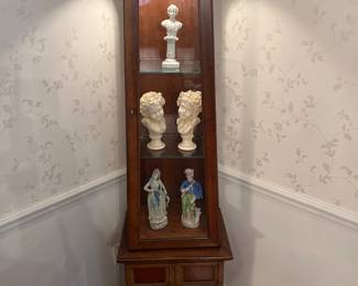 Dining Room: A lighted pyramid shape display cabinet has three shelves over two lower doors. It measures 18" wide x 14" deep x 68" tall. The displayed figures are also priced.