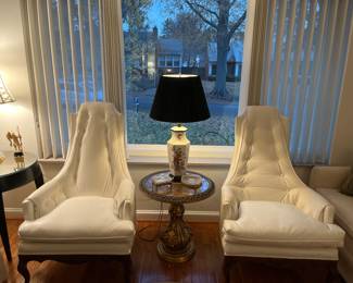 Living Room:  Two mid-century style high-back/tufted chairs flank a vintage Italian gold gilt pedestal table with "marbleized" mirror top.  The Asian style porcelain lamp has a black base and black shade.