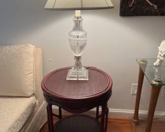 Living Room:  One of two separately priced crystal lamps with a Lucite base rests on a round rattan accent table with under-shelf.
