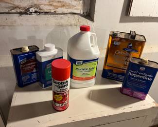Scotchgard, Muriatic acid, turpentine, mineral spirits and boiled linseed oil all displayed on a wooden cabinet.