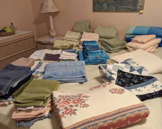 Queen size bed with matching sheet sets and assorted linens.