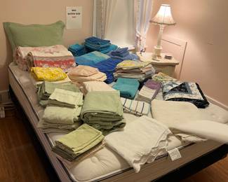 Beach towels, hand towels, wash cloths,   Queen size sheet sets, bed spreads and blankets all displayed on a Queen sized bed.