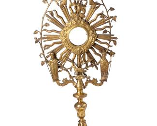 2037
19th century
A Large Gilt Bronze Monstrance
Appears unmarked
The dore liturgical vessel, possibly Latin American, comprised of an elaborate top solar or sunburst section adorned with applied saints and symbolic figures and animals, surrounded by grape vine tendrils and surmounted by a crown with bells and a cross, with a round central receptacle, all mounted atop an elaborate repoussé and stamped base, with further stamped motifs to stem
27" H x 12.5" W x 7.75" D
Estimate: $1,000 - $1,500