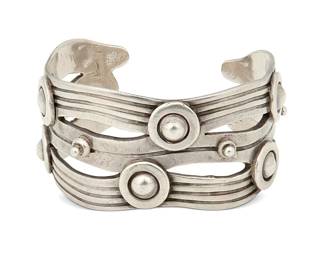 2110
A William Spratling "River Of Life" Silver Cuff Bracelet
William Spratling (1900-1967)
Circa 1944-1946, First Design Period; Taxco, Mexico
Stamped for William Spratling; further stamped: Made in Mexico / Silver
Designed as incised silver waves with applied narrow Aztec rings
6.625" total inner C x 1.375" H. with a 1.125" gap
87.2 grams
Estimate: $400 - $600