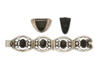 1169
A Group Of Silver And Obsidian Jewelry
Three works:
Frederick W Davis (1880-1961)
Pre-1948; Mexico City, Mexico
A silver and stone set brooch
Stamped FD / silver / Made in Mexico
A silver brooch with central set carved obsidian mask
1.25" H x 2" W
A sterling silver link bracelet
Stamped: Sterling / Mexico
An openwork sterling silver link bracelet with central carved set obsidian
7.25" L x 1.375" H
A carved obsidian mask
Unmarked
1.5" H x 1" W
3 pieces
65.0 grams gross
Estimate: $600 - $800