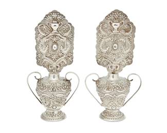 1059
Early/mid-20th century
A Pair Of Silver Candle Screens
One with handwritten cloth label: FD 144
Possibly a model for a Fred Davis design, the two silver candle screens with ornate repoussé floral and garland motifs above a handled and footed vase-form base with conforming repoussé motifs, 2 pieces
Each: 8.75" H x 4.5" W x 2.75" D
12.6 oz. troy approximately
Estimate: $500 - $700