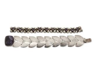 1176
Two Mexican Silver Bracelets With Set Amethysts
Mid-20th century
Each stamped: Silver / Made in Mexico
Two Fred Davis-style link bracelets, one with herringbone links and large cushion cabochon amethyst clasp (7.5" L x 1.125" H), and one with silver "caviar" floral motif links. each with central set small amethyst cabochon (6.25" L x 0.5" H), 2 pieces
84.3 grams gross
Estimate: $400 - $600