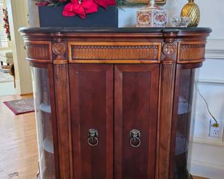 Foyer cabinet with detailed wood work and curved glass doors on side