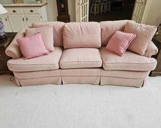 Pink three seat upholstered sofa has matching loveseat