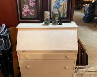 The pair of framed artwork of purple and blue irises sitting on the top of the secretary's desk are pleasant images.