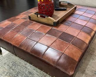 Woven leather ottoman with brass casters and brass tacks.