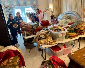 25 totes full of antique vestments, fabrics, tapestries, needlepoints, etc.   before picture of the gals hanging them all!