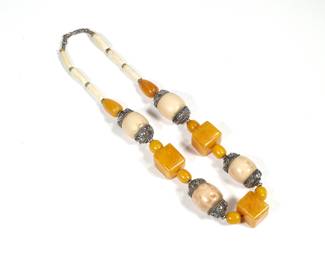 UNUSUAL CARVED BONE & AMBER NECKLACE | Having four oval carved bone links (26mm) with silver mounts alternating with three cube-form amber links (26mm); 23 in., 165g

