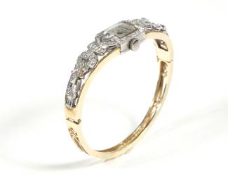 DIAMOND & GOLD LADY'S WATCH HARD BRACELET | The top section comprised of sections of a diamond-encrusted platinum art deco wristwatch mounted on a newer openwork gold hard bracelet; 28.0g. - dia. 2 in.
