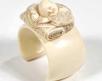 SLEEPING BOY CHINESE CARVED BANGLE BRACELET | an open carved bone bangle bracelet mounting a carved figure of a sleeping boy; h. 3 x 2.75 in., 82.9g
