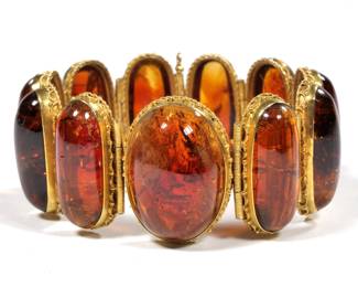 ANTIQUE AMBER TOURMALINE LINK BRACELET | Having ten well-matched links of oval amber tourmaline cabochons (29 x 12 x 7 in., each approx.) and one central cabochon (30 x 22 x 9.8mm) each in a gold ropework surround with coiled hinge links
7 in., 79.5g
