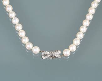 PEARL NECKLACE WITH DIAMOND CLASP | Designed as a strand of white 9 mm pearls terminating in a platinum and diamond bow-form clasp; 16 in., 44.7 g
