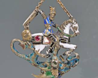 ENAMEL DECORATED ARTICULATING KNIGHT & DRAGON PENDANT | Designed as guilloche enameled knight on horseback (possibly St. George) wearing a winged helmet and wielding a sword intertwined with a dragon with articulating wings, mounted with one ruby and one emerald and suspending a single seed pearl, hanging from a fine link chain. 20.8g, l. 1.75 in.
