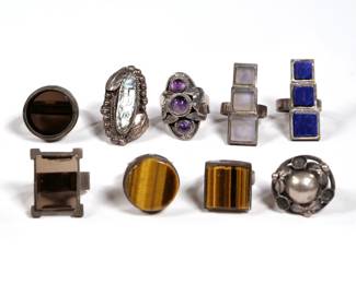 (9pc) STERLING SILVER RINGS | Including a Mexican Taxco de los Ballestros ring with three amethyst cabochons, the central stone fixed to a hinged lid revealing a secret compartment; a Carl Frydensberg Skonvirke ring, two tiger's eye rings (one round, one square), two smoky quartz rings (one round, the other rectangular), an old Mexican abalone ring, and two similar triple square rings, one with lapis, the other with quartz or glass; all together 3.1 ozt (97.0g)

