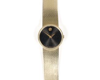 MOVADO WOMAN'S 14K GOLD WRISTWATCH | Black dial with gold dot numeral, 14k and with swiss hallmarks, s/n 1143002. 37.0g, l. 7 in.

