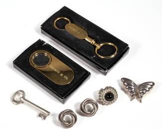 (7pc) TIFFANY & CO. JEWELRY | Including a butterfly pin, a 1994 key-shaped pin, a pair of Mexican sterling knotted earrings, and a single earring with brown or purple cabochon, accompanied by a blue Tiffany box; plus a gold-tone Tiffany & Co. keychain and loupe, each in a black Tiffany box; total weighable silver 1.32 ozt

