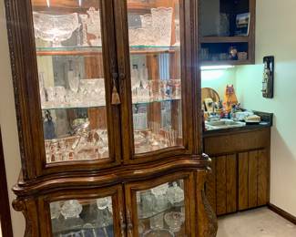 Solid wood, lighted and glass china cabinet with claw feet. Filled with wonderful crystal pieces, one being a French Duck silver plated Duck Decanter. Mikasa etched glass new in box
