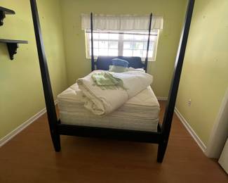 Queen sized four poster black bed has two small matching night