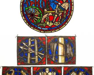 A Gothic Revival Stained Glass Guild panels.  Multi-color stained and leaded glass panels with reverse painted details, includes a roundel after a Guild window at the Chartres Cathedral, and five square panels depicting various trade emblems.  Panels intact with minor flakes to edges, wear to paint.  Roundel is 15 1/2" diameter, others each 8 1/4 x 8 1/4" high overall.