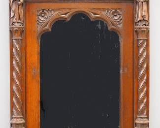 An early 20th century Gothic carved Oak mirror retailed by Lightolier, New York.  Carved rectangular frame with arcaded crown above an arched mirror with carved tracery and two rope twist columns surmounted by carved Apostles.  Original "Lightolier, New York" embossed foil tag at back.  Older finish with minor wear, lacks some decorative elements at top and sides.  25 x 36" high overall.