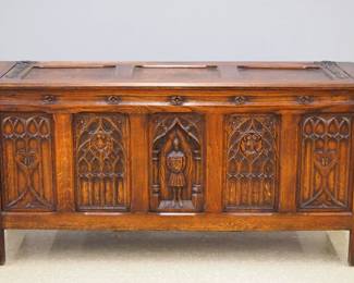 A turn of the century Gothic Revival Period carved Oak side buffet.  Molded top over two doors with carved tracery and central figural panel, with carved columns surmounted by Apostle figures, Iron hinges and lock.  Old finish with wear, some shrinkage, break to one Iron strap hinge.  48 1/2 x 21 x 33 1/2" high overall.