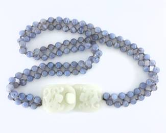 A turn of the century Chinese Jade belt.  Features a carved White Jade buckle with Dragon design on a belt with two strands of hand-knotted Blue Lace Agate beads.   Minor surface wear, lacks some inter-strand knots by buckles.  38 1/2" long open.