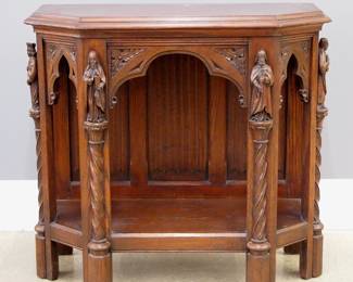 A turn of the century Gothic Revival Period carved Oak console table.  Molded top with canted corners over an arched flat carved skirt and open lower shelf with linen fold carved back panel, on carved legs with rope twist columns surmounted by Apostle figures.  Stenciled "Made in Belgium" at back.  Refinished with minor wear and fading to top, small chip to one Apostle's hand.  35 x 16 x 32" high overall.
