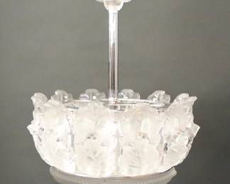 A 1960's Lalique "Chene" Crystal chandelier.  Elaborate three light chandelier with single tier molded Oak leaf design and frosted detail in a circular Chrome frame with molded Crystal canopy.  Etched signatures "Lalique France".  Slight wear, minute flakes at the edges of four leaves and the back of another.  22 1/2 x 27" high overall.   ESTIMATE $4,000-6,000   PROVENANCE: From the Estate of Richard P. Kughn, Dearborn, Michigan.