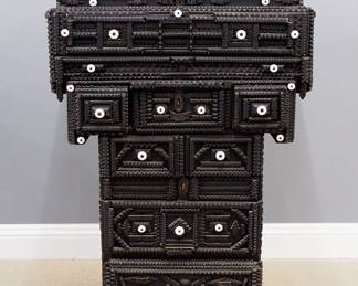 A turn of the century American Tramp Art tall chest by James S. Henderson inscribed "Cabinet Started January 1, 1900, Finished 1905, Aug 25… Study Out Oct 20, 1882 Model".  Constructed of scrap wood and found objects including a crate side labeled "High Explosives, Dangerous" decorated with chip carved Hearts, Stars, Diamonds outlined with stacked zipper moldings and applied detail.  Retains its original Black painted finish highlighted with a multitude of White porcelain knobs and various metal objects.  Features an upper lift top divided compartment over two long drawers, two short and three short and two long lower drawers.  Original finish with some wear and minor damage.  18 x 38 1/2 x 54" high overall.  ESTIMATE $2,000-4,000  Note:  From the Collection of Connie Covent, "Sign of the Windsor Chair" Antiques, Clarkston, Michigan