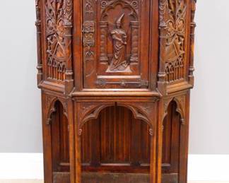 A turn of the century Gothic Revival Period carved Oak court cupboard.  Molded top with canted corners over one central door with carved tracery and figural panel, rope twist columns surmounted by carved Apostles, over an open lower shelf with linen fold carved back panel, Iron hinges and lock.  Original finish with wear, some damage and shrinkage, burn mark to top.  34 x 18 1/2 x 55" high overall.