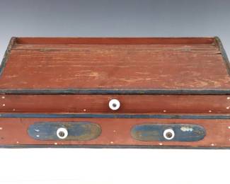 A 19th century American painted wood writing slope.  Pine construction with original Red and Blue painted finish, features a hinged writing slope over two long graduated drawers with applied bosses and porcelain knobs.  Wear to paint, minor damage.  19 3/4 x 11 1/4 x 8" high overall.