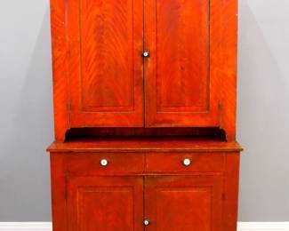 A 19th century American painted step back cupboard.  Maple construction in two parts with a molded cornice over two raised panel doors and a short pie shelf in the upper and two short drawers, raised panel doors and a cut out bracket base below.  Original Red/Yellow grain painted finish.  Some wear, upper interior with later paint, rodent damage to drawers, lacks keeper on bottom doors.  18 x 46 1/2 x 81 1/2" high overall.