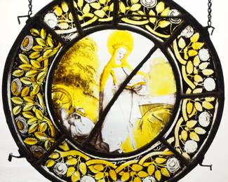 A Gothic Revival Stained Glass roundel of Saint Catherine, German or French.  Yellow stained and leaded glass panels with reverse painted detail depicting Saint Catherine of Alexandria with sword and wheel.  Panels intact, wear to paint with some surface scratches.  13 1/2" diameter.