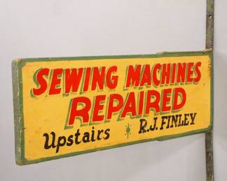 A turn of the century wooden Trade Sign advertising "Sewing Machines Repaired, Upstairs - R. J. Finley".  Double sided painted wooden sign with iron brackets.  Some surface wear.  20 1/2" long x 7 1/4" high plus brackets make it 22 1/2" high overall.
