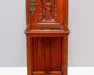 A turn of the century Gothic Revival Period carved Oak side cupboard.  Molded top over one central door with carved tracery and figural panel, flanked by rope twist columns, over an open lower shelf with linen fold carved back panel, Iron hinges and lock.  Old finish with minor wear, shrinkage and some lifting.  18 1/2 x 15 x 51 1/2" high overall.