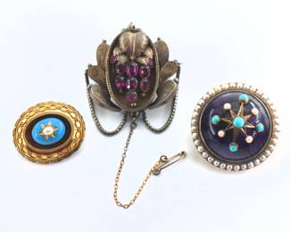 Three 19th century British Victorian Period brooches.  Includes an 14k Gold mourning brooch with cabochon Amethyst stone, Turquoise and Pearl star design and Pearl surround, a Gold Filled mourning brooch with engraved grape design and nine faceted Amethyst stones, and a Gold Filled brooch with Blue enameled boss, inlaid Pearl star and decorative milgrain border.  Amethyst and Turquoise/Pearl mourning brooch unmarked but tested 14k, grape design mourning brooch with British 1868 kitemark.  Some wear overall, chip to Blue enamel.  Up to 1 5/8" high.