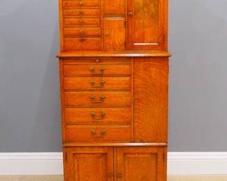 A turn of the century American Dentist's cabinet by the "American Cabinet Co, Two Rivers, Wis, USA".  Oak construction with stepped case containing multiple drawers, doors and pull-out storage racks.  Refinished with some wear, lacks interior dividers and one door knob.  15 1/2 x 27 x 59" high overall.